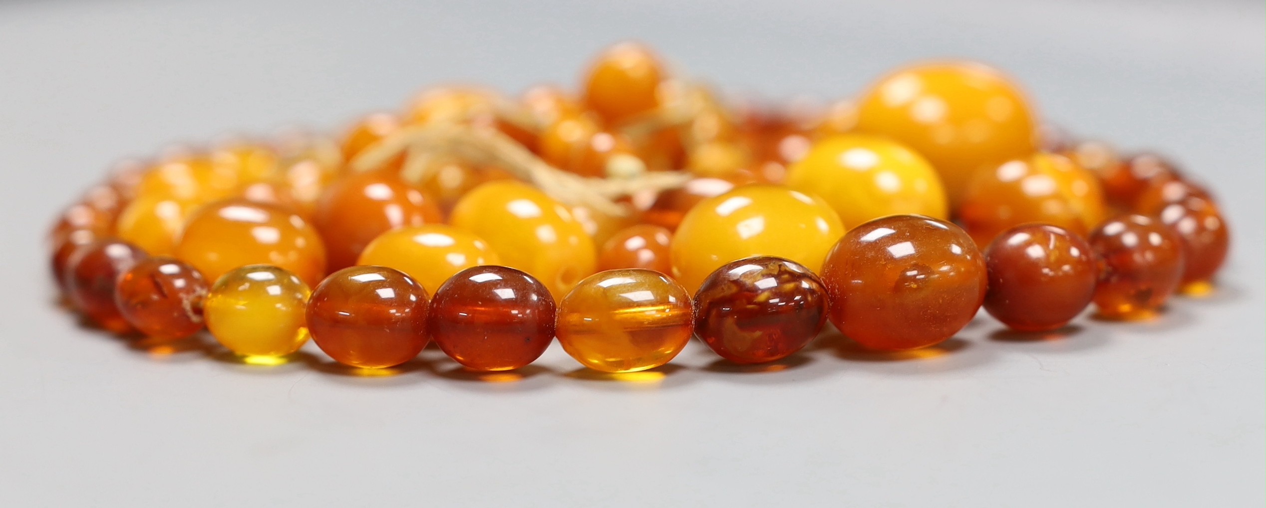 A quantity of loose amber beads, 53 grams and a bead necklace, 18.8 grams